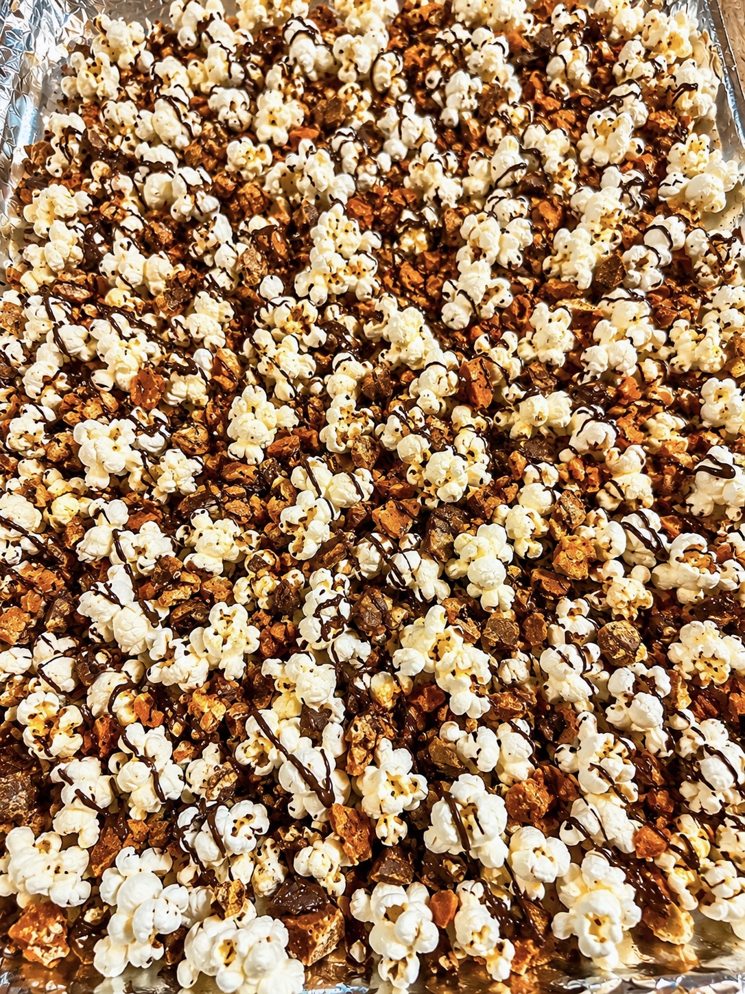 Popcorn covered in chocolate drizzle and golden candy crumble
