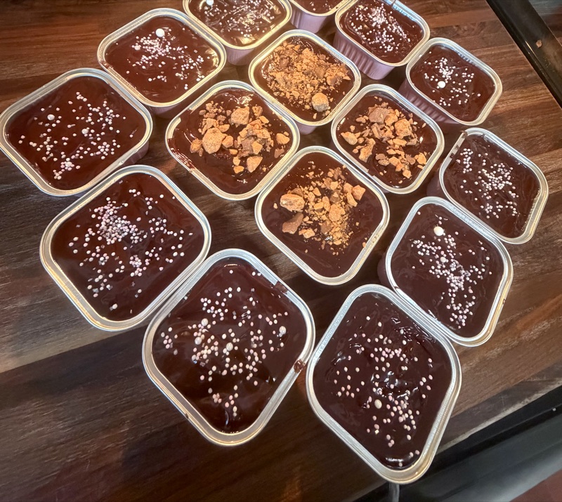 An assortment of chocolate-topped brownie tins with pink and white sprinkles and candy pieces